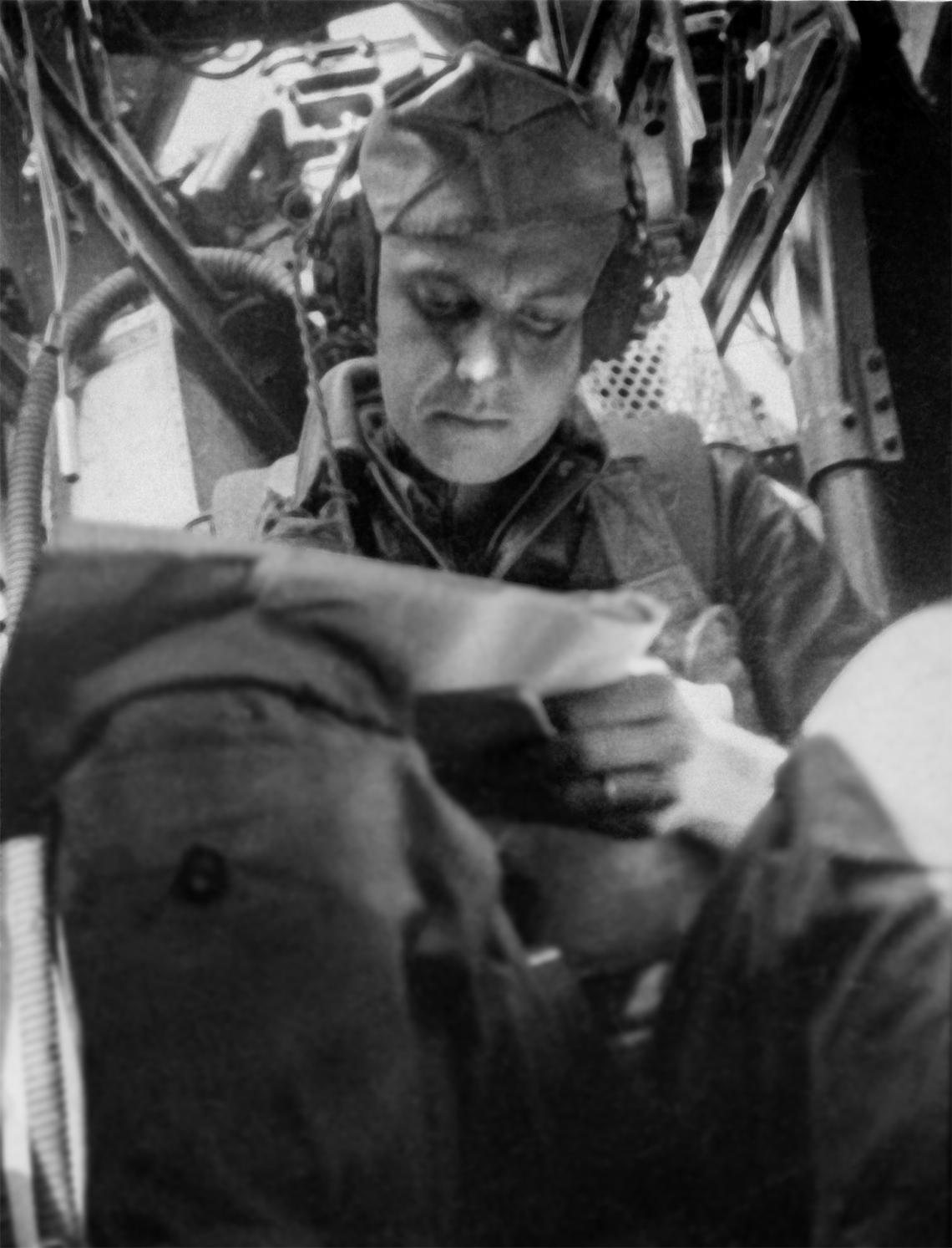 Navigator John R. Barnes in the nose of a B-17, looking down at a chart