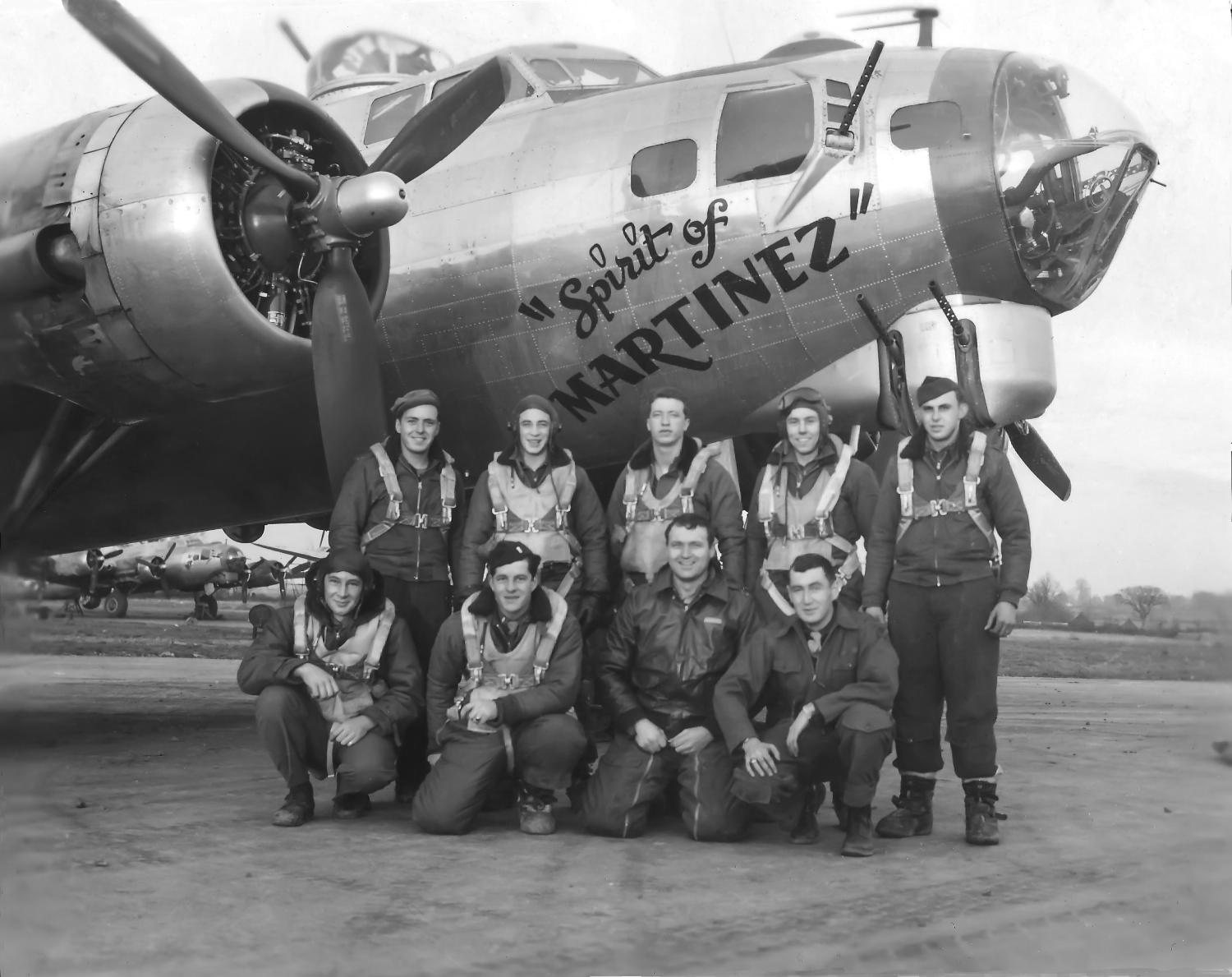 Nine airmen posed in two rows under the nose of a B-17 painted Spirit of Martinez