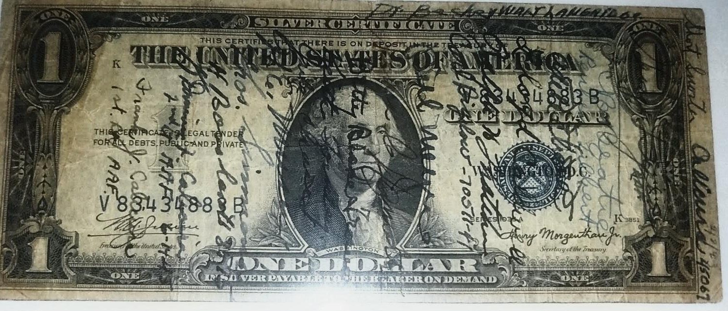 A worn one-dollar silver certificate covered in overlapping wartime signatures, Washington at the center